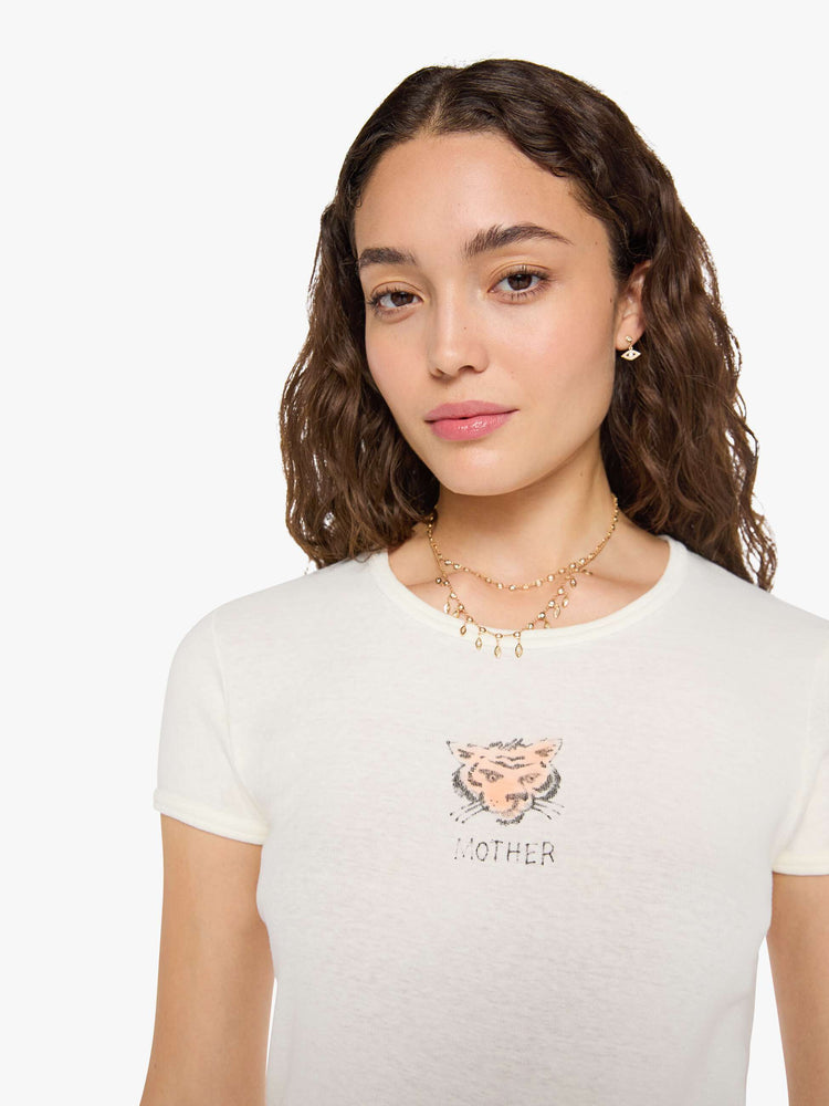 Close up view of woman in an off-white tee features a faded, air-brushed tiger graphic and MOTHER's name in black on the front.
