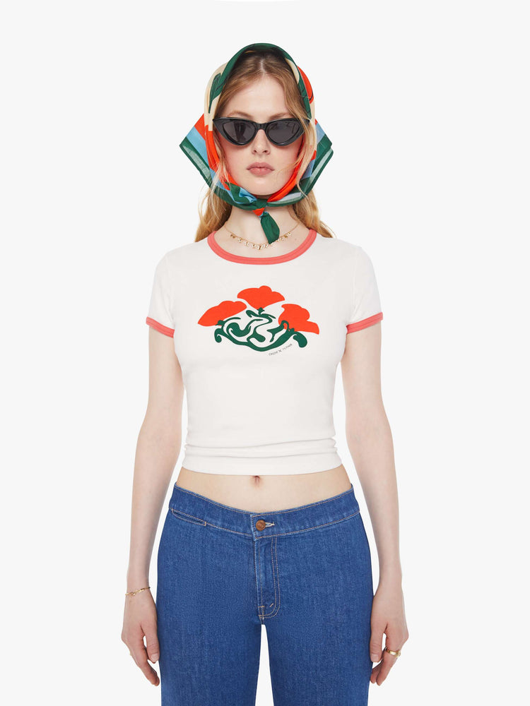 Front view of a woman in a white with faded red trim with an abstract rose graphic crewneck tee with extra-short sleeves and a cropped hem. 