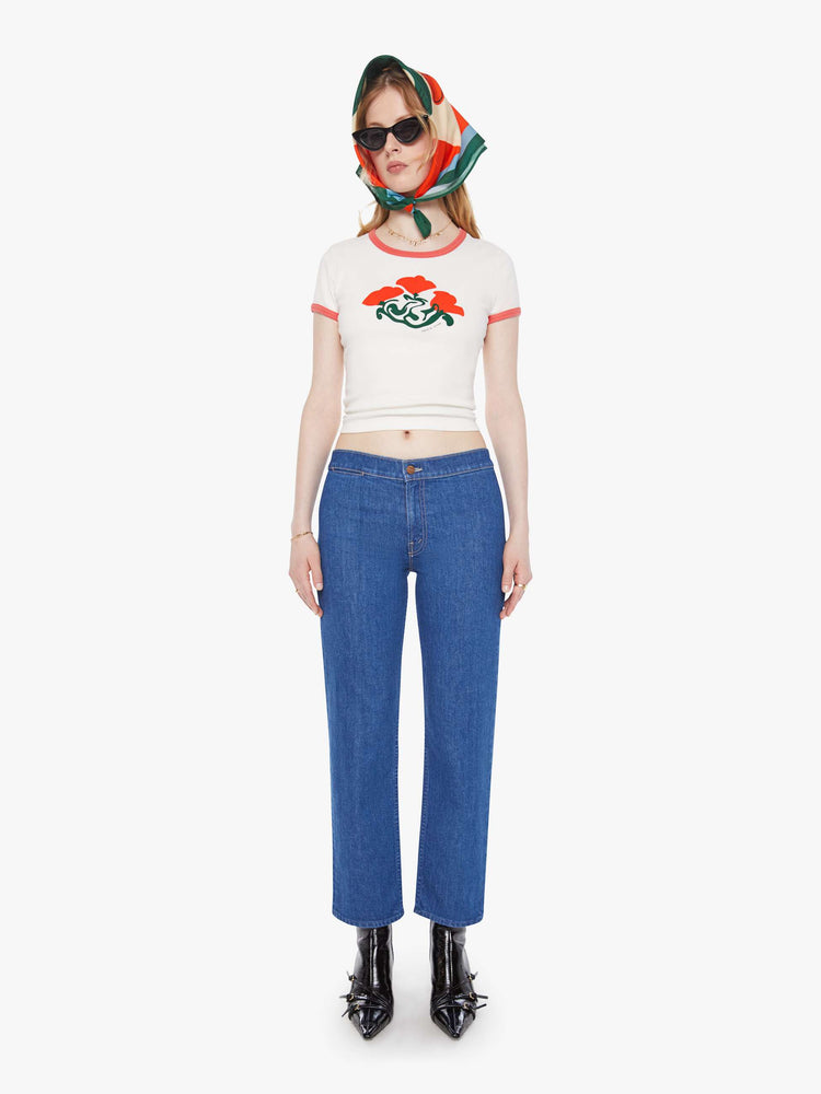 Full body view of a woman in a white with faded red trim with an abstract rose graphic crewneck tee with extra-short sleeves and a cropped hem. 