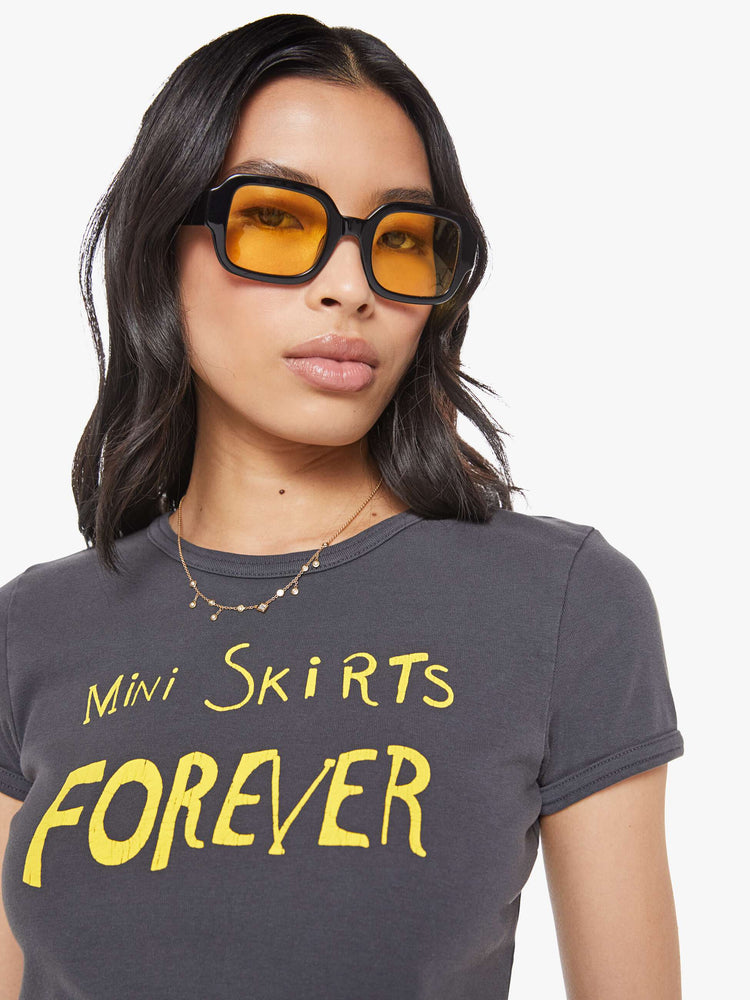Close up view of a  faded black tee with a Mini Skirts Forever features yellow text on the front.