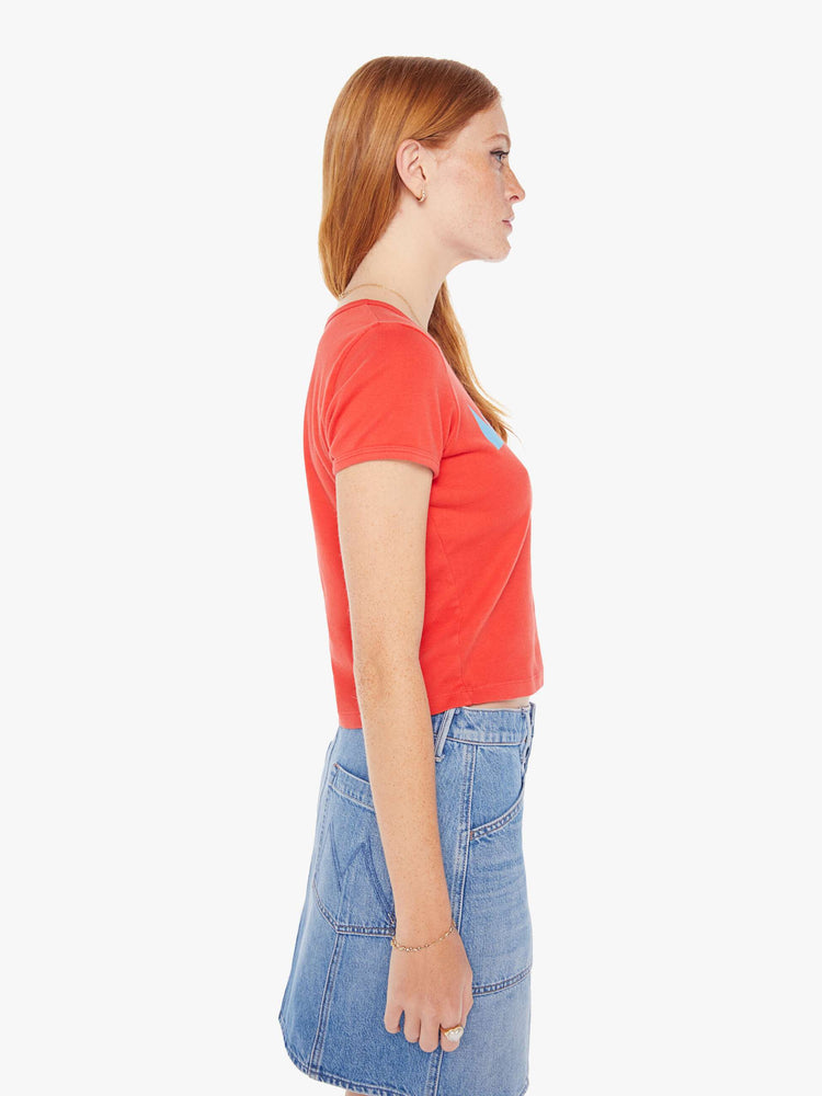 Side view of a woman hrunken crewneck tee with extra-short sleeves and a cropped hem in red with a blue and orange text graphic.