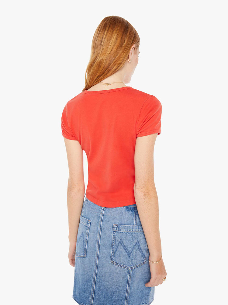 Back view of a woman hrunken crewneck tee with extra-short sleeves and a cropped hem in red with a blue and orange text graphic.