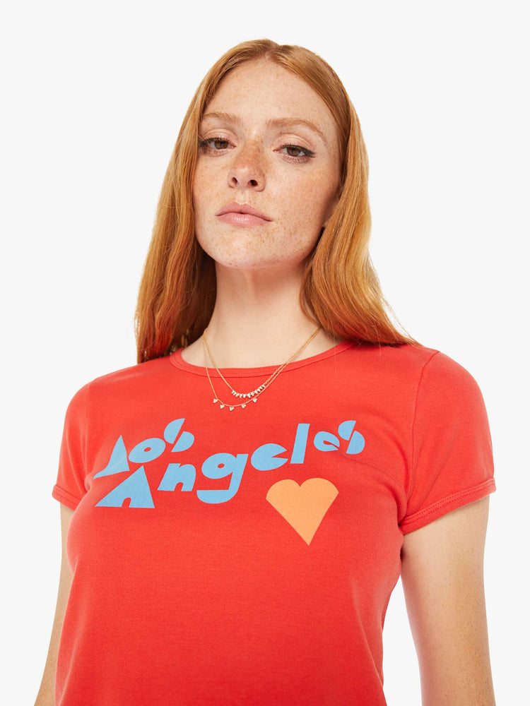 Close up view of a woman hrunken crewneck tee with extra-short sleeves and a cropped hem in red with a blue and orange text graphic.