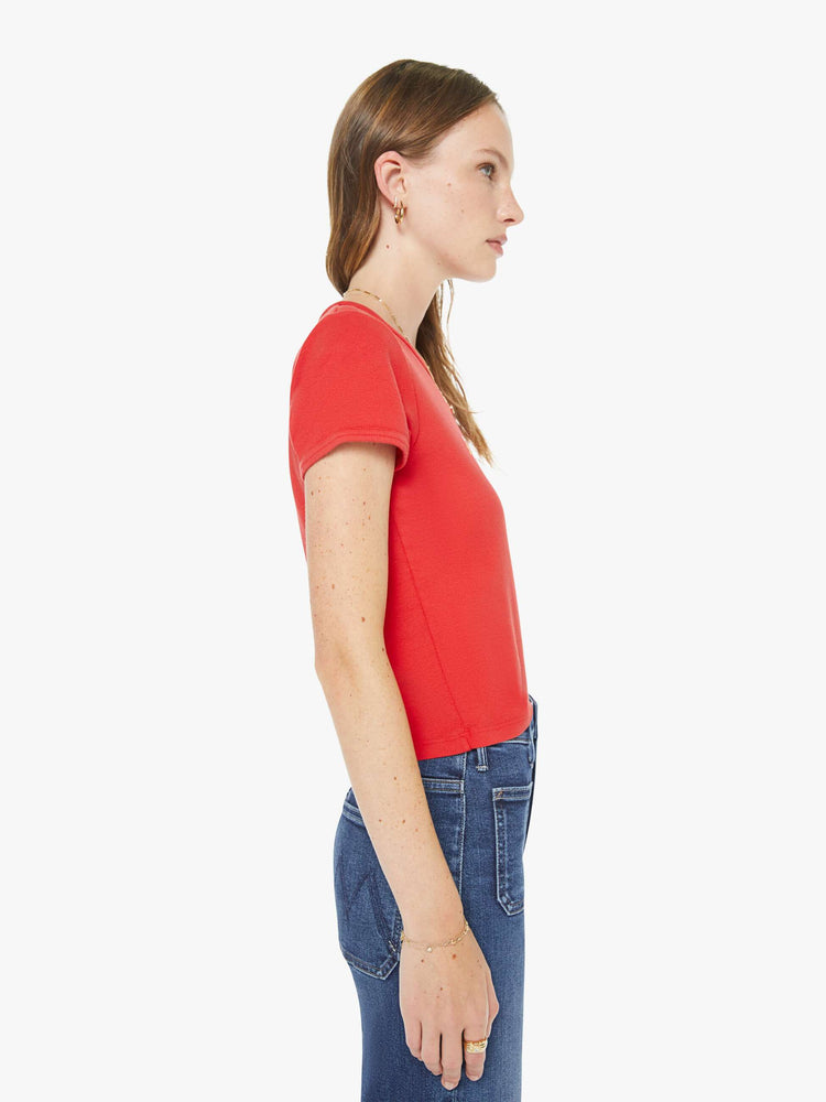 Side view of a woman in a red tee with a white text graphic with flowers on the front.