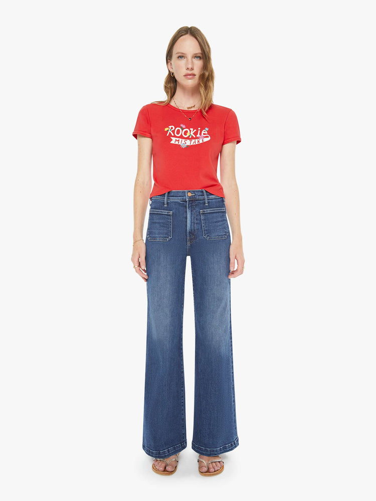 Full body view of a woman in a red tee with a white text graphic with flowers on the front.