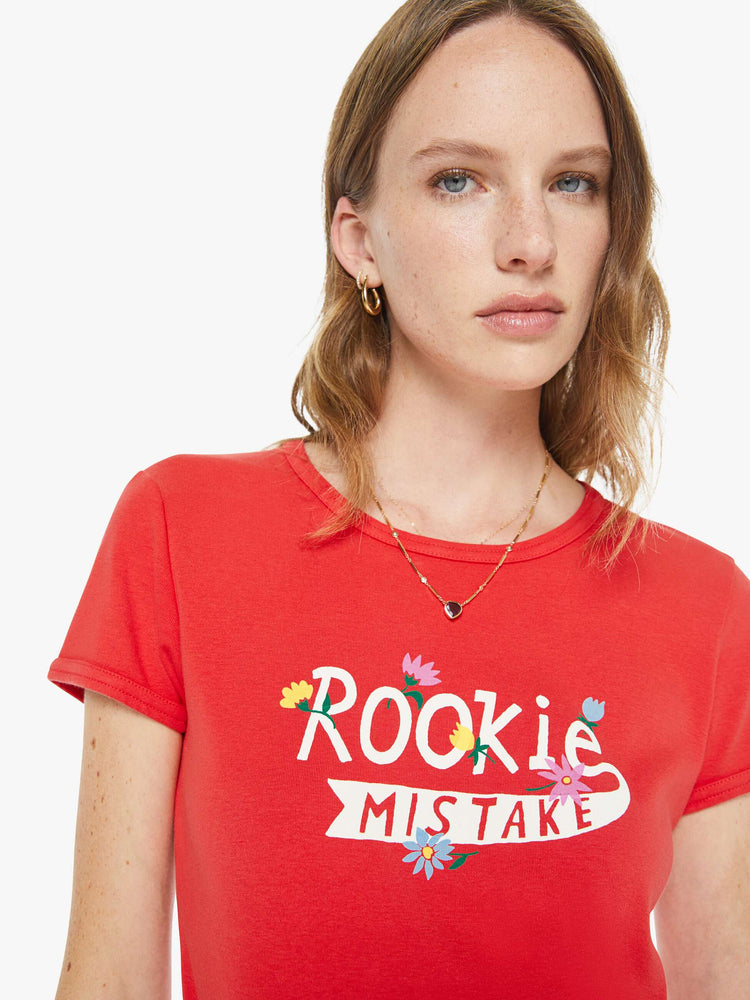 Close up view of a woman in a red tee with a white text graphic with flowers on the front.