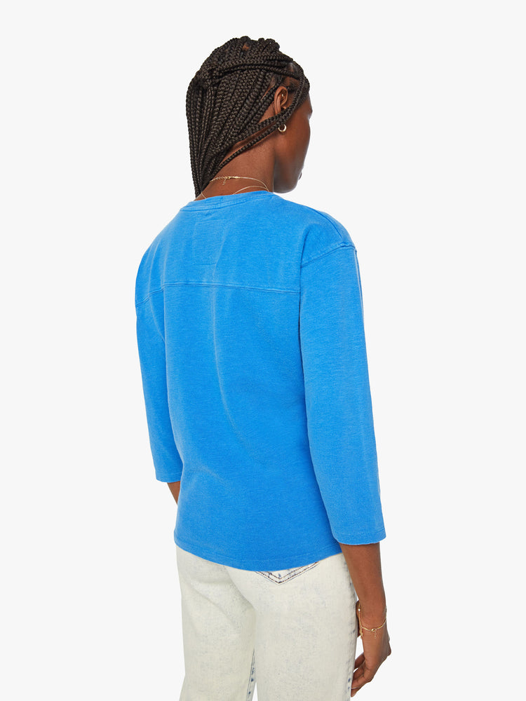 Back view of a women football tee with a boat neck, 3/4 sleeves, drop shoulders and a boxy fit in blue with number 32 and text in red.