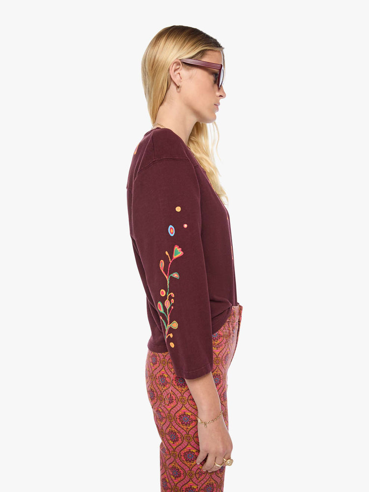 Side view of a woman in a  3/4 sleeves and a boxy fit tee with colorful bird on the front, hand-drawn doodles throughout and MOTHER's name across the back.