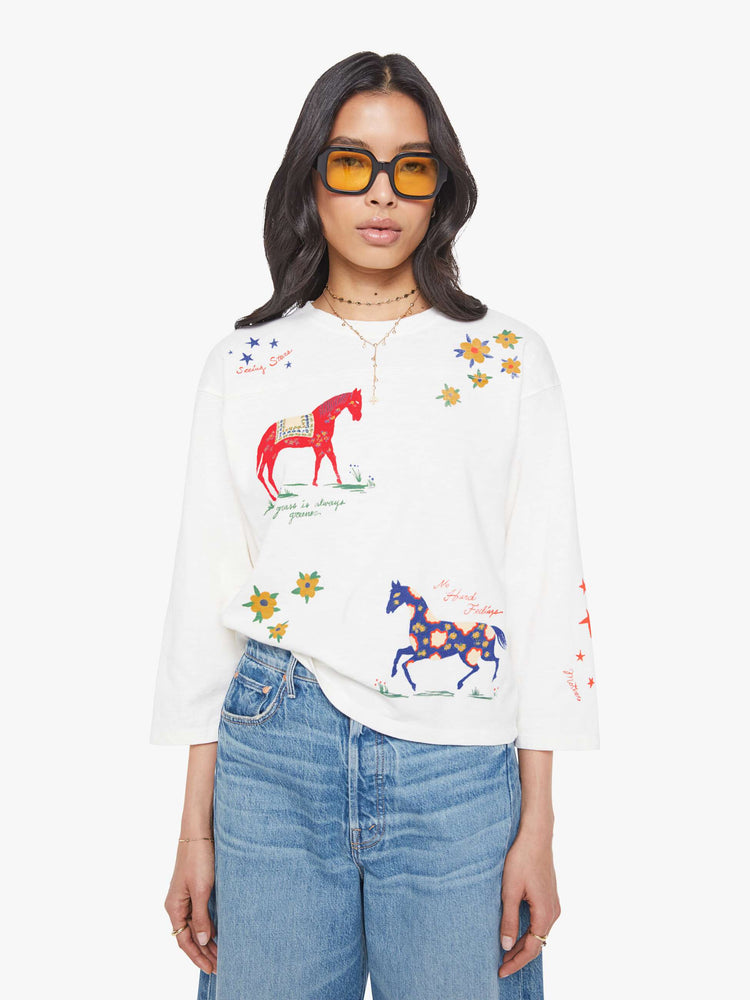 Front view of a woman in horse and flower white oversized crewneck tee is designed with drop shoulders, 3/4 sleeves and a boxy fit.