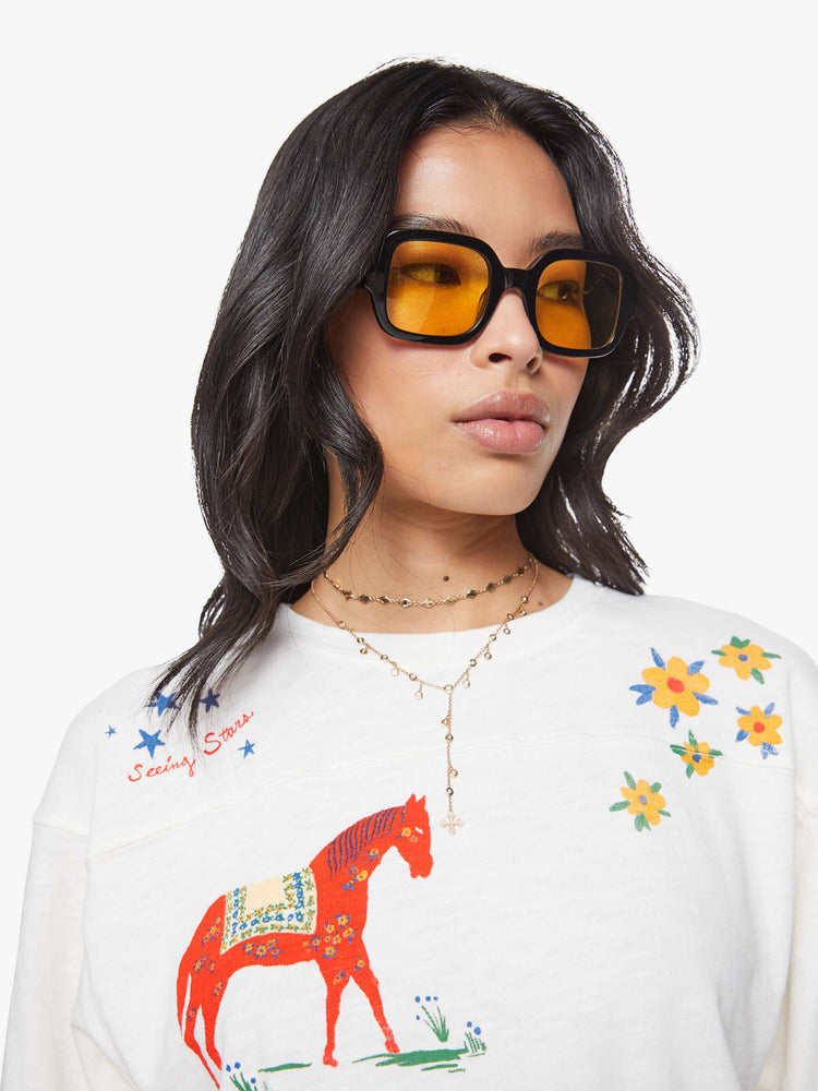 Close up view of a woman in horse and flower white oversized crewneck tee is designed with drop shoulders, 3/4 sleeves and a boxy fit.