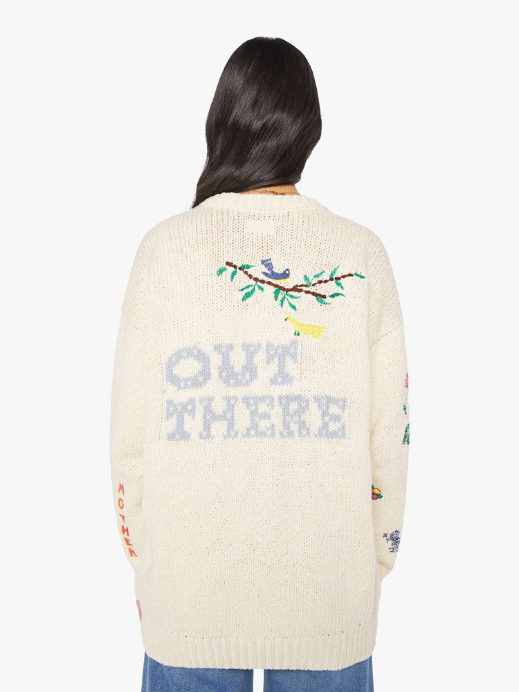 Back view of a woman in a cream with colorful embroidery  oversized crewneck cardigan with drop shoulders, patch pockets and ribbed hems. 