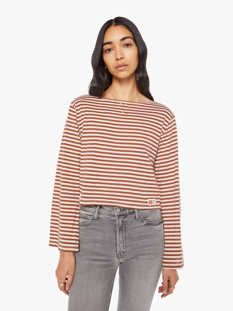 Front view of a woman in horizontal brown and white stripes long sleeve tee with a boat neck and boxy fit.