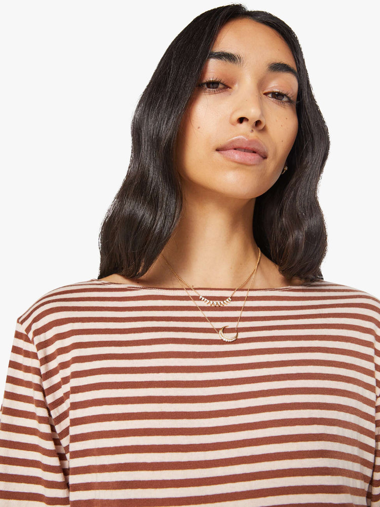 Close up view of a woman in horizontal brown and white stripes long sleeve tee with a boat neck and boxy fit.