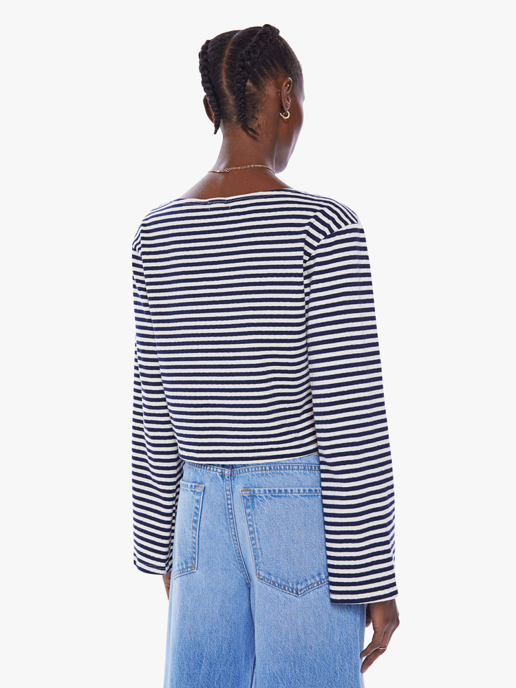 Back view of a woman navy and white stripe boatneck top with long sleeves, drop shoulders, a cropped hem and boxy fit.