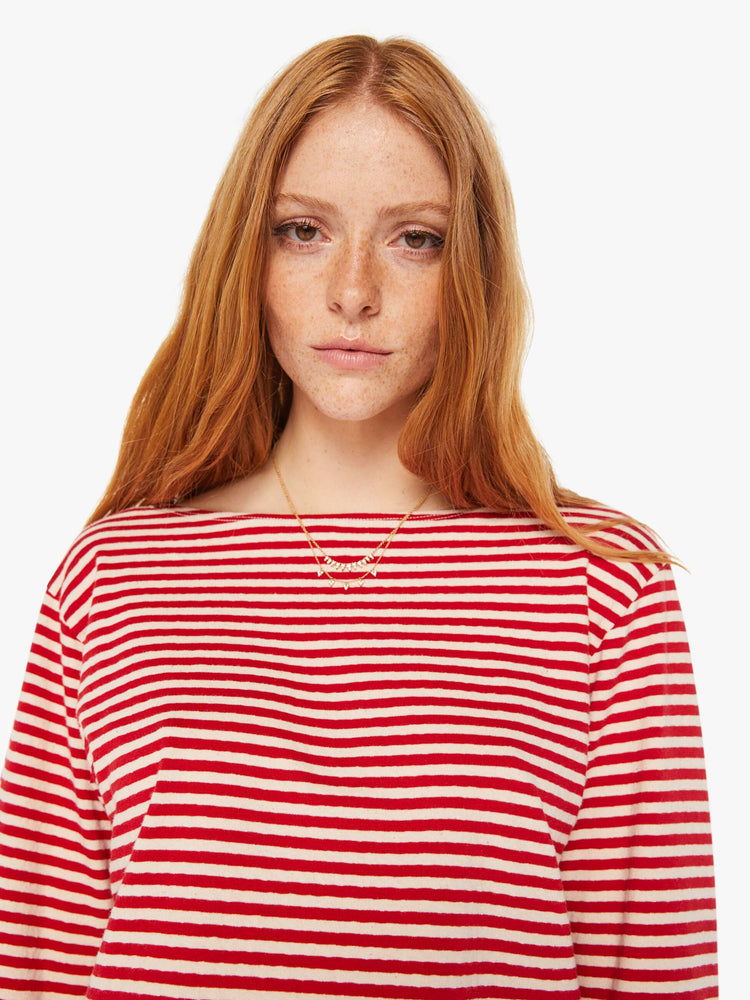 Close up view of a woman red and white stripe pattern boatneck top with long sleeves, drop shoulders, a cropped hem and boxy fit.