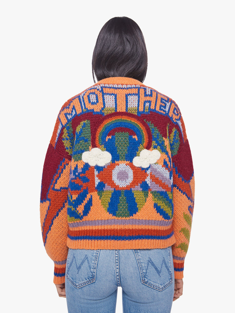 Back view of woman chunky knit cardigan, ribbed hems and a deep V-neck with buttons down the front in a colorful psychedelic print.