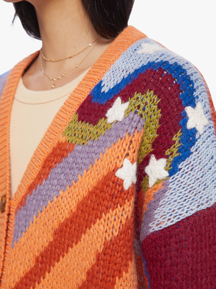 Close up view of woman chunky knit cardigan, ribbed hems and a deep V-neck with buttons down the front in a colorful psychedelic print.