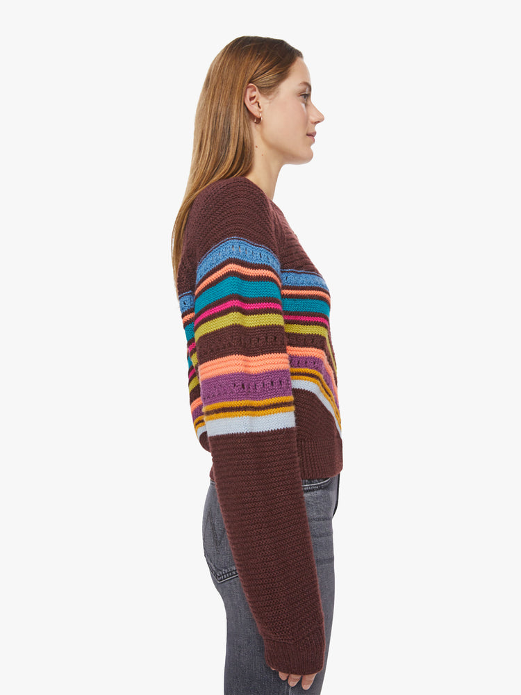 Side view of a woman raglan sweater with a crewneck, extra-long sleeves and a slightly cropped hem in a maroon hue with colorful stripes and eyelet details.