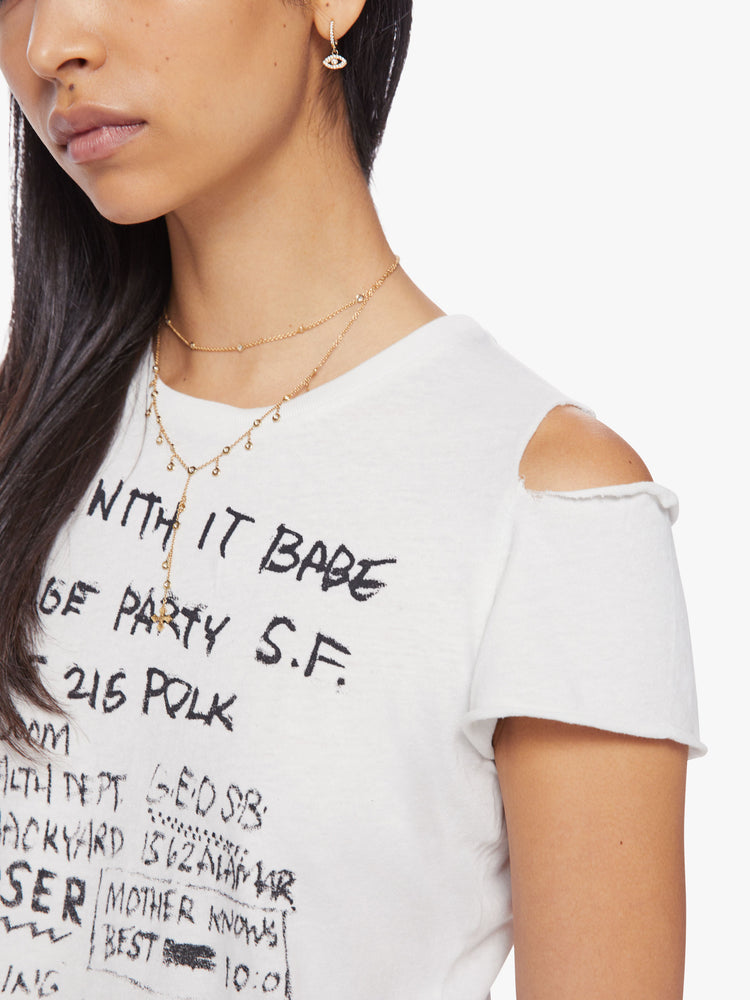 Close up view of a woman cropped crewneck tee with a raw hem and ripped shoulder seam in white with the tee features a hand-drawn coming-to-terms text graphic in black on the front.