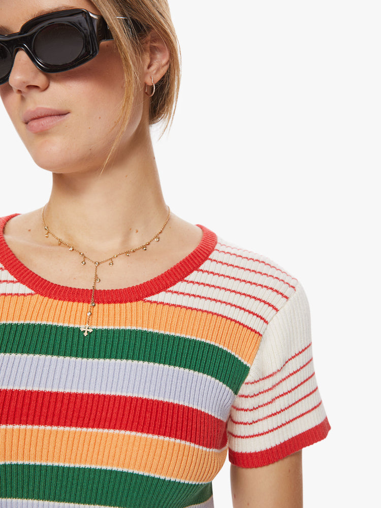 Close up view of a woman rainbow stripe scoop neck tee with short sleeves, a slim fit and a cropped hem.