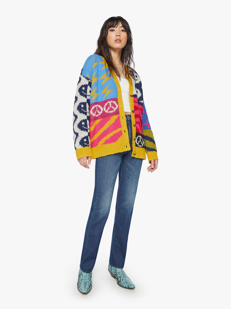Full body view of a woman oversized V-neck cardigan with drop shoulders, long balloon sleeves and ribbed hems in graphic smiley faces, peace signs, lightning bolts and zebra print.