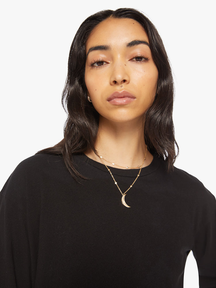 Close up view of a womens long sleeve crew neck tee in Black featuring a cropped raw cut hem.