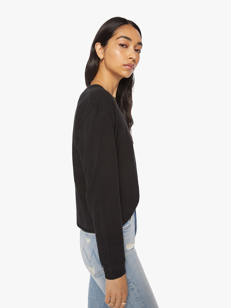 Side view of a womens long sleeve crew neck tee in Black featuring a cropped raw cut hem.