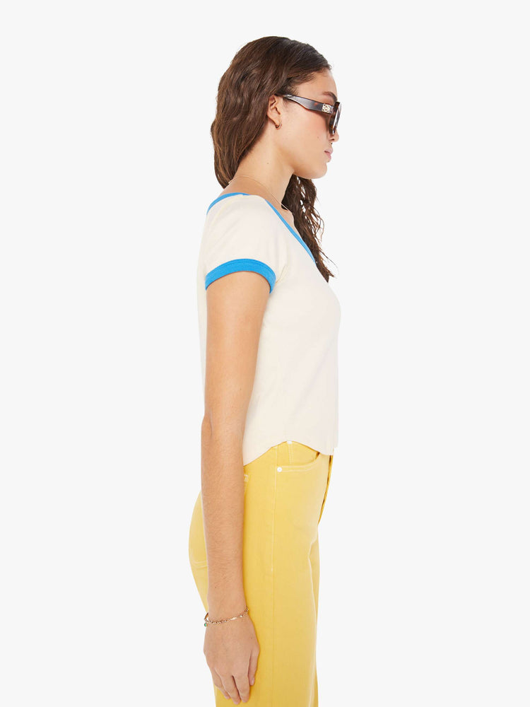 Side view of a woman in a baby tee designed with a deep scoop neck, short sleeves, a slim fit and a cropped, curved hem.