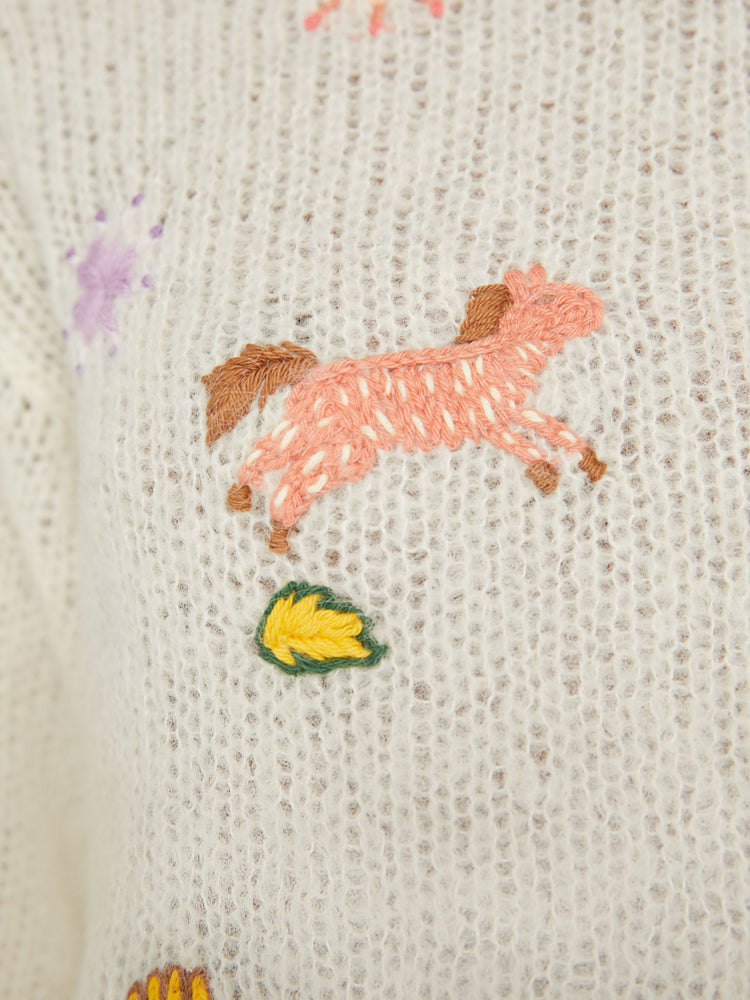 Swatch  view of woman boatneck sweater with long sleeves, drop shoulders, a cropped hem and boxy fit in an off white with colorful embroidered flowers, horses and other Western-inspired charms.