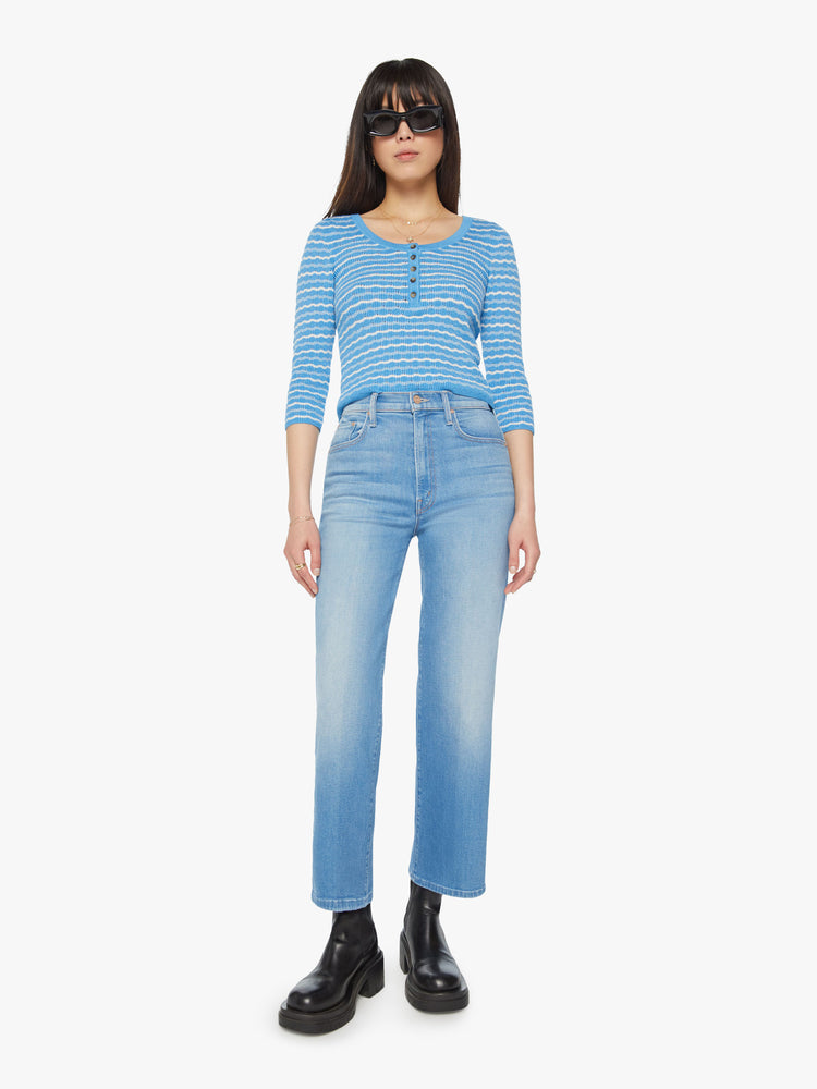 Full body view of a woman cropped henley with a buttoned scoop neck, 3/4-length sleeves and a slightly shrunken fit in a baby blue and white stripe pattern.