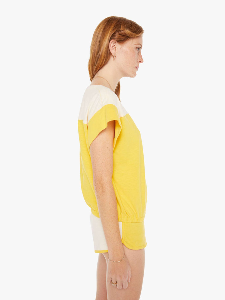 Side view of a womens yell and white top featuring a boat neck and elastic hem.
