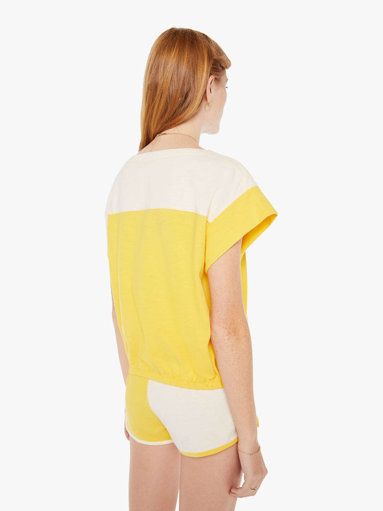 Back view of a womens yell and white top featuring a boat neck and elastic hem.