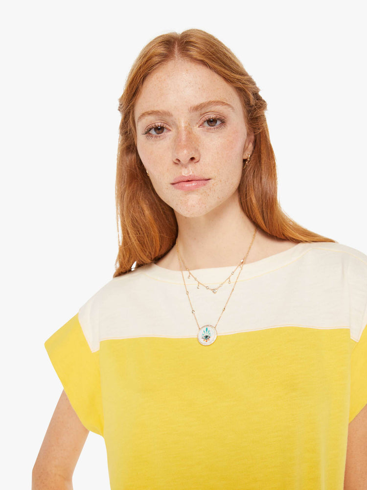 Front close up view of a womens yell and white top featuring a boat neck and elastic hem.