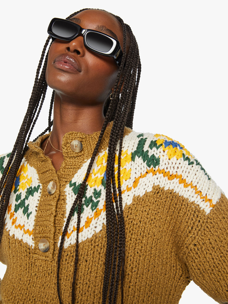 Close up view of a woman chunky knit sweater with a buttoned crew neck, drop shoulders and ribbed hems in a mustard yellow with floral details and a red bull on the back.