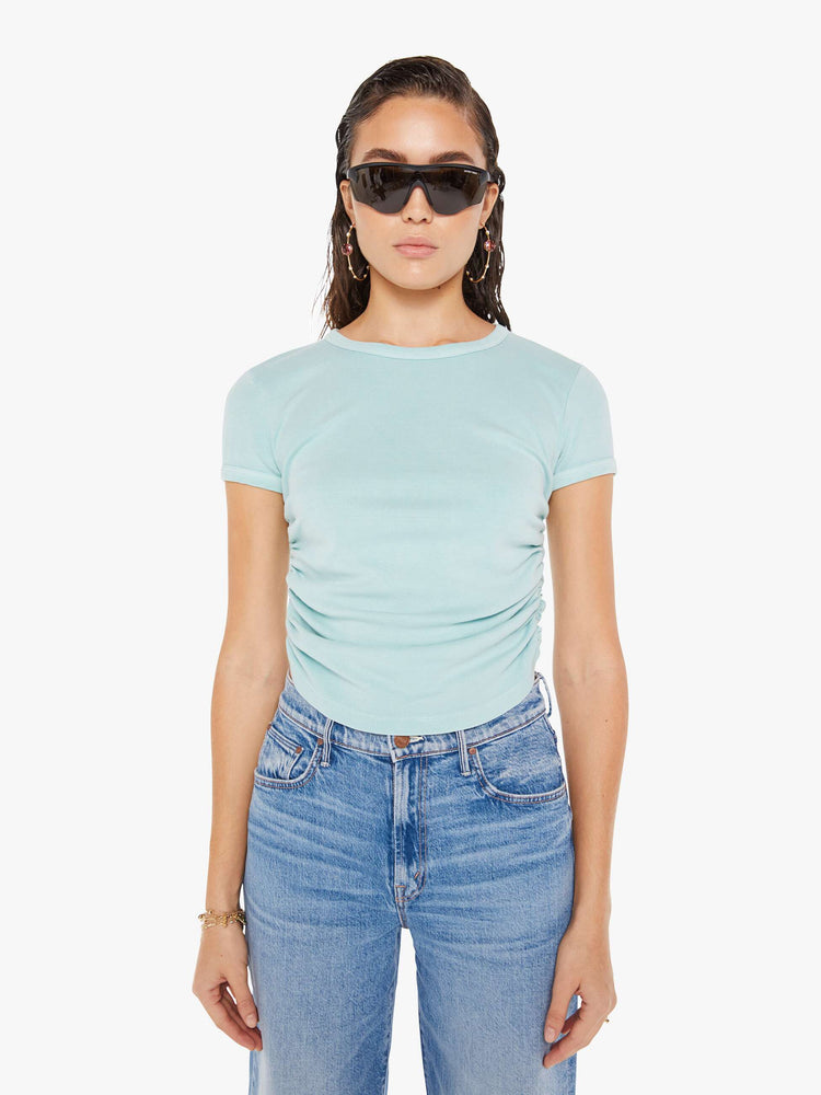 Front view of a woman wearing am eggshell blue crew neck tee featuring cinched side seams, paired with a medium blue wash jean.