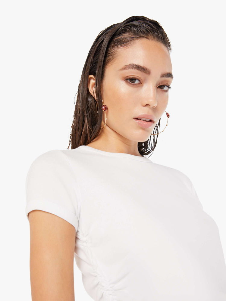 close up view of a woman wearing a white crew neck tee featuring cinched side seams.