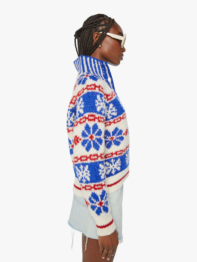Side view of a woman chunky knit sweater with a buttoned funnel neck, subtle balloon sleeves and a slightly cropped fit in a white, red and blue traditional Nordic snowflake pattern.