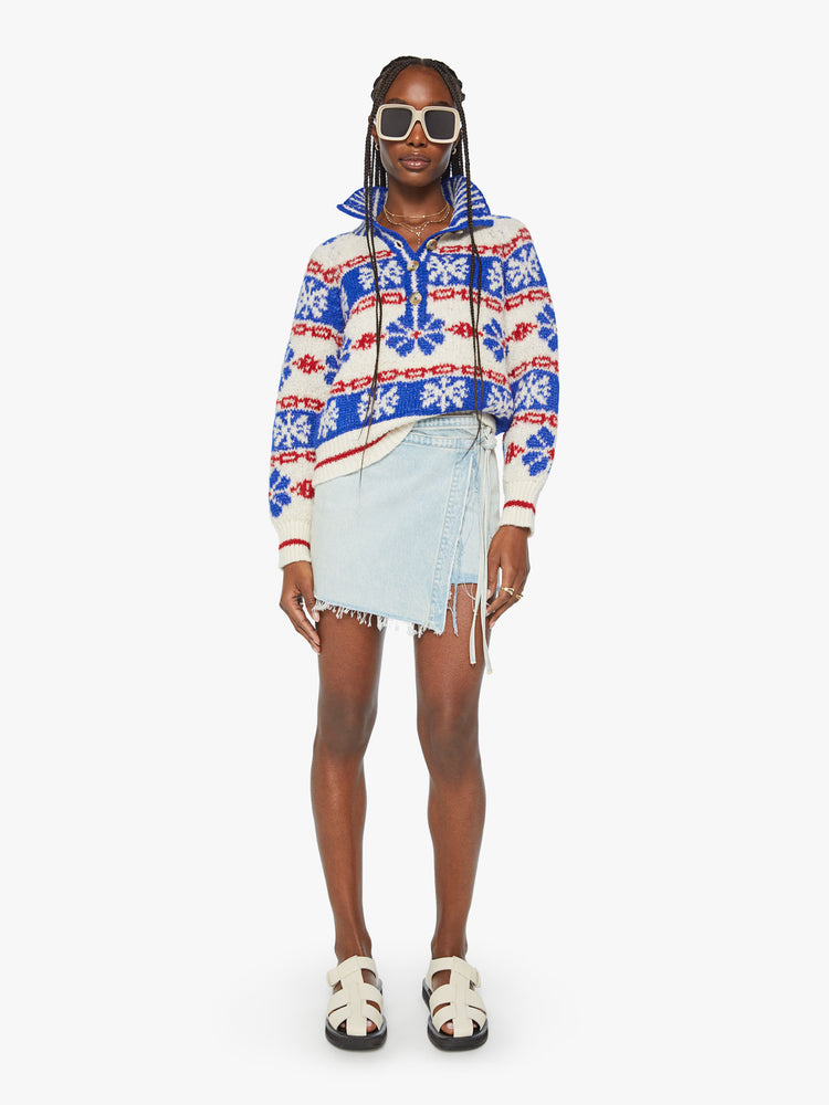 Front view of a woman chunky knit sweater with a buttoned funnel neck, subtle balloon sleeves and a slightly cropped fit in a white, red and blue traditional Nordic snowflake pattern.
