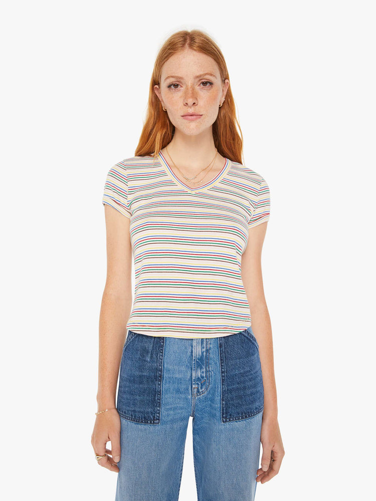Front view of a woman baby tee with a V-neck, short sleeves and a slim fit in white with rainbow stripes throughout.