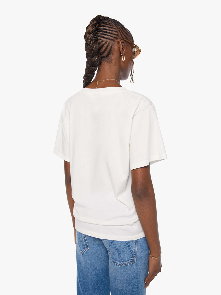 Back view of a woman in an off white  V-neck tee with drop shoulders and a loose, boxy fit. 