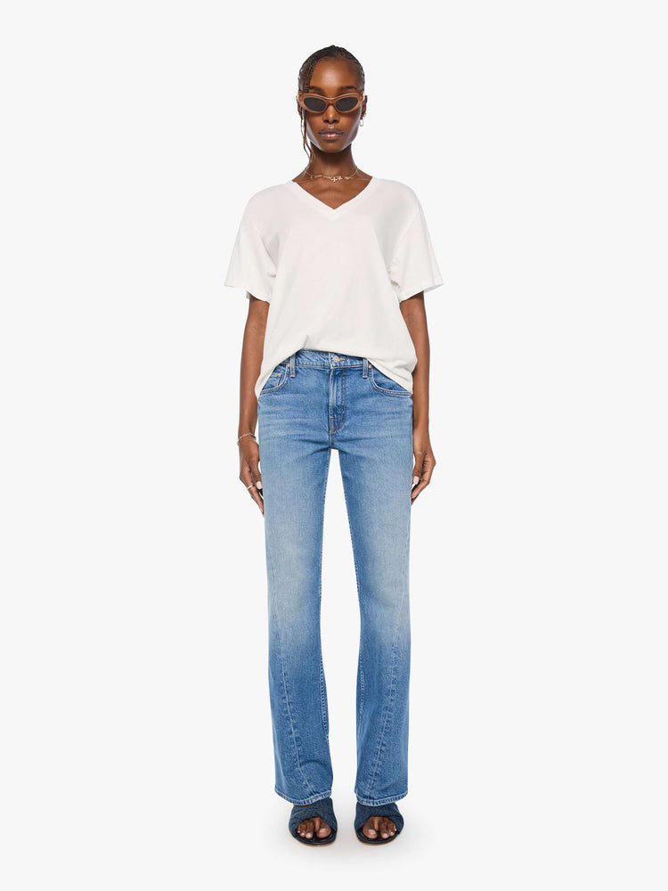 Full body view of a woman in an off white  V-neck tee with drop shoulders and a loose, boxy fit. 