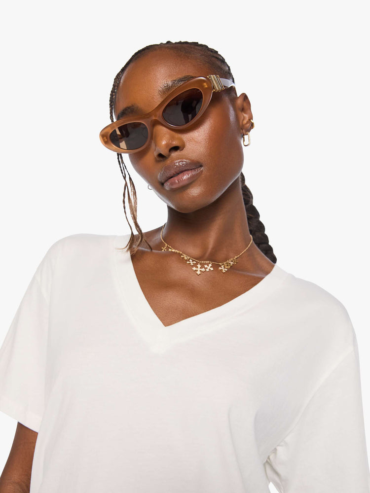 Close up view of a woman in an off white  V-neck tee with drop shoulders and a loose, boxy fit. 