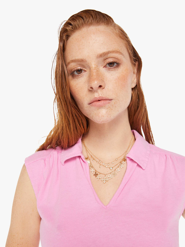 A front close up view of a woman wearing a pink polo collar tee featuring cap sleeves.