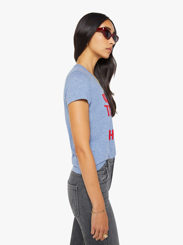 Side view of a woman in a heathered blue tee features a red block text applique on the front.