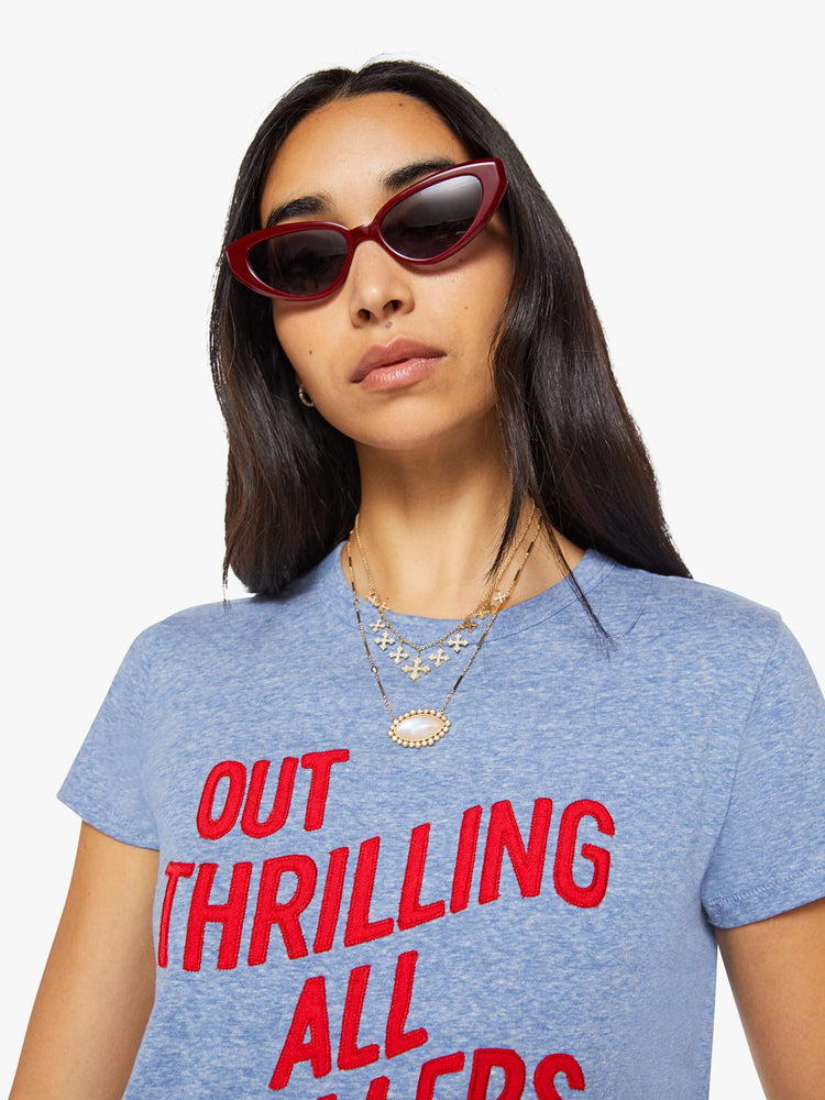 Close up view of a woman in a heathered blue tee features a red block text applique on the front.