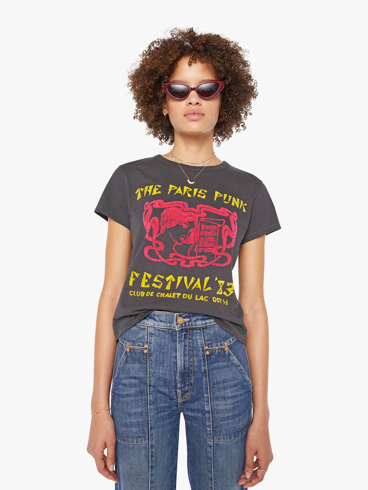 Front view of a woman in a faded black tee features a yellow and red text graphic inspired by a punk music festival.