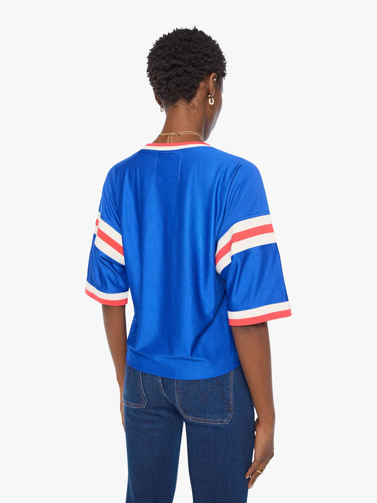 Back view of a woman in top is made from bright blue mesh with red and white striped details on the neck and sleeves and MOTHER's name in white across the chest.