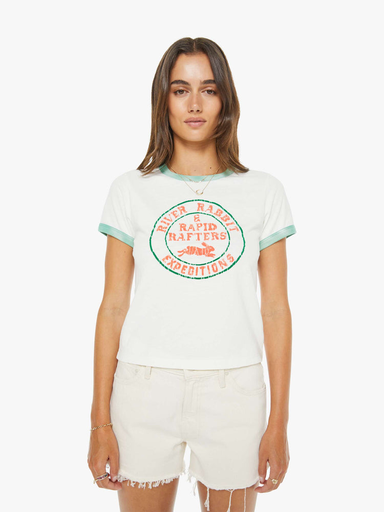 Front view of a woman in a white with green trim tee with a flocked graphic on the front inspired by a rafting expedition logo.