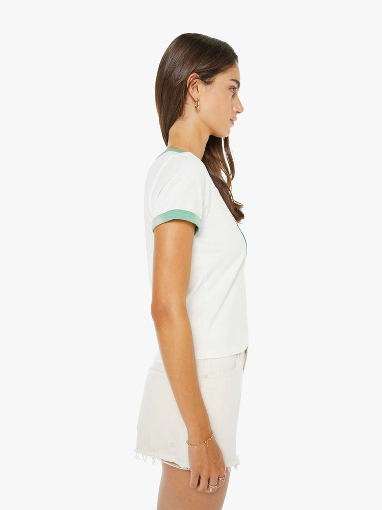 Side view of a woman in a white with green trim tee with a flocked graphic on the front inspired by a rafting expedition logo.