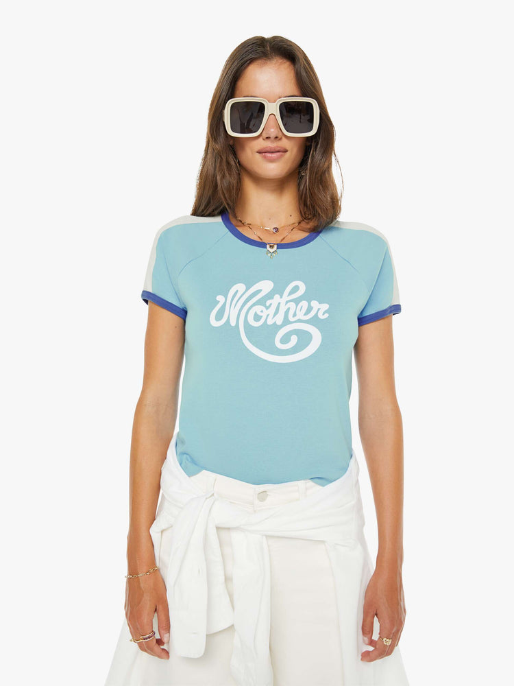 Front view of a woman in a  baby blue tee features navy trim, white panels on the shoulders and MOTHER's name in cursive on the front.